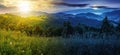 panorama of mountainous summer landscape with forested hills and grassy meadow beneath a sky with sun and moon at twilight Royalty Free Stock Photo