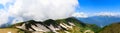 Panorama of the mountains and Aibga Ridge with low clouds. Remnants of snow and new green grass on Mountains near the