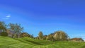 Panorama Narrow paved road on a vast grassy terrain under blue sky on a sunny day