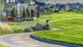 Panorama Narrow paved road that winds through vast grassy terrain viewed on a sunny day