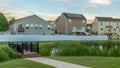 Panorama Neighborhood park with pond bridge pathway bench and trees in front of homes