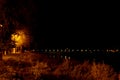 Panorama of the night city in the orange light of lanterns, bridge over the river, reflection of lights in the water Royalty Free Stock Photo