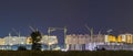 Panorama night view of many building cranes at construction site Royalty Free Stock Photo