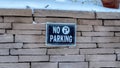 Panorama No Parking sign on a stone brick retaining wall topped with snow in winter Royalty Free Stock Photo