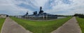 Panorama of an old battleship in Texas in water near a green area with a small footpath