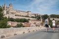 Panorama of old roman bridge with couple of tourists and cathedral St Nazaire in Beziers the city in south France