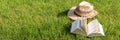 Panorama. Open book lies on a lawn with straw hat in the background. Relaxation in the garden during coronavirus pandemic Royalty Free Stock Photo