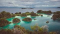 Panorama of Pianemo island overgrown with jungle plants, surrounded by shallow turquoise colored ocean lagoon. White