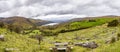 Panorama picture of typical Irish landscape with green meadows and rough mountains Royalty Free Stock Photo