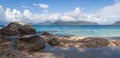 A panorama of a picturesque deserted blue lagoon with a sandy beach, a pleasant shade from a palm tree on a hot tropical day