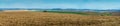 Panorama of plowed fields among the hills and are forests and distant mountains on horizon Royalty Free Stock Photo