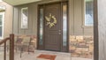 Panorama Porch and front door of a home with wood and stone brick wall sections