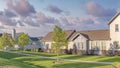 Panorama Puffy clouds at sunset Row of houses with lawn and two concrete walkways on the sides a Royalty Free Stock Photo