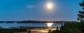 Panorama of rising full golden Moon over Umea river delta, summer night with clear skies and tiny white fog over water and coast Royalty Free Stock Photo