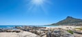 Panorama of a rocky beach near the ocean and mountain on a sunny day in South Africa. Landscape wallpaper of a coastline Royalty Free Stock Photo