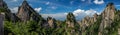 Panorama of rocky peaks and old pine trees cover the mountains under a bright blue sky with whispy clouds in Huangshan China