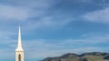 Panorama Rooftop and steeple of a church against power lines mountain and blue sky