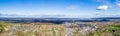 Panorama on hilly area with forests, fields, houses and highways in sunlight against a cloudy sky Royalty Free Stock Photo