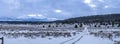 Panorama of a rustic wintery scene with tire tracks along a dirt road in the freshly fallen snow in northern California, USA