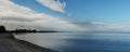 Panorama of the sea strecthing out into the bay with a calm sea and cloud filled blue sky