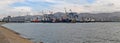 Panorama of the sea trade port with a view of container ships, pilot boats and many different port cranes.