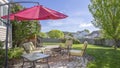 Panorama Seating area on a stone patio under the shade of a red umbrella on a sunny day