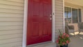 Panorama Shiny red wooden front door of a home with wicker chairs on the sunlit porch Royalty Free Stock Photo