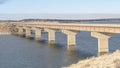 Panorama Shore blanketed with fresh snow overlooking a bridge across vast lake in winter