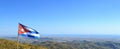 Panorama shot of Cuban flag waving on a pole with nature landscape of Cuba in background Royalty Free Stock Photo