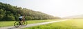 Panorama shot of cyclist on racing cycle in a rural landscape in summer with scenic lens flare