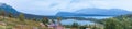 Panorama shot of Old farm houses and gravel road leading towards lakes and mountains in the background.