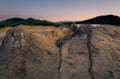 Panorama shot of some of the craters at Muddy Volcanoes in Romania, Buzau County with the mountains in the background