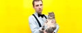 Panorama shot of thoughtful man in blue shirt, black suspender and bow tie holding grey striped tabby cat