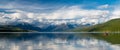 Panorama of snow-capped mountains and red boat reflected in calm lake Royalty Free Stock Photo