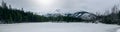 Panorama. A snow-covered pond surrounded by snow-capped mountains. Tatra National Park. Koscieliska Valley, Pond Smreczynski,