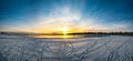 The panoroma of yellow horizon and sunset in snow-covered sea beach during winter