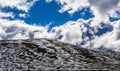 Panorama of Snow patches on mountains and fluffy clouds on bright sunny day Royalty Free Stock Photo