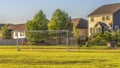 Panorama Soccer goal on vast green grassy field in front of houses viewed on a sunny day