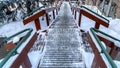 Panorama Stairway and road on snow covered hill amid houses and coniferous trees