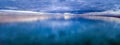 Panorama of stormy clouds over smooth ocean water surface.