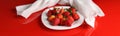 Panorama with strawberries and a white towel on a glossy red table