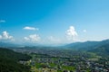 A panorama of successive mountain slopes, lost in a haze, against a background of blue sky and white cumulus clouds.