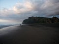 Panorama sunset view of tourist walking along black sand Karekare Beach West Auckland North Island New Zealand ocean Royalty Free Stock Photo