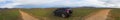 Panorama with SUV and dirt road leading to the mountains Royalty Free Stock Photo