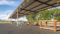 Panorama Tables and benches under flat corrugated metal roof of a pavilion at a park