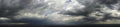 Panorama of thunderstorm, clouds and sunbeams shining through the clouds Royalty Free Stock Photo