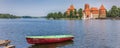 Panorama of Trakai castle and a red and green boat in lake Galve