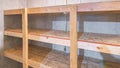 Panorama Unfinished small storage room with concrete walls and wooden shelves