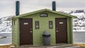 Panorama Unisex public restroom against lake snowy mountain and cloudy sky in winter Royalty Free Stock Photo