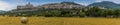 A panorama view across a field of hay towards the hill town of Assisi, Umbria, Italy